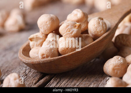 raw chickpeas in a wooden spoon macro and scattered on the old table horizontal Stock Photo