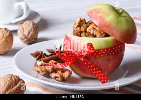 Red apple with nuts and raisins on a white plate and coffee on the table. Horizontal close-up Stock Photo
