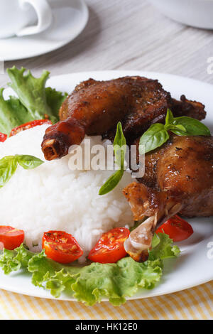roasted duck leg with rice and tomatoes on a plate close up vertical Stock Photo