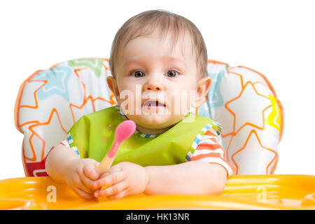 Little baby are eating. Kid boy sitting with spoon at table. Stock Photo