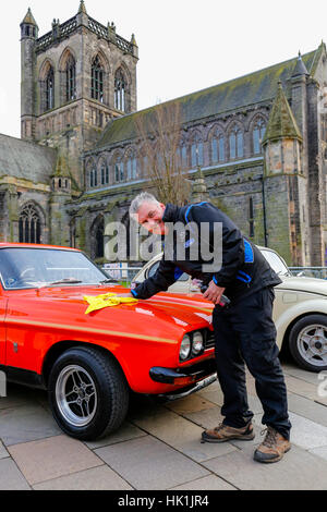 Paisley, Scotland, UK. 25th January 2017. Over 10000 spectators turned out in Paisley town centre, outside the town's famous historical abbey to cheer off the 80 entrants to this years Monte Carlo Rally. The image is of KEN TODD from Stirling polishing his 1973 Ford CApri RS3100 before the race begins Credit: Findlay/Alamy Live News Stock Photo