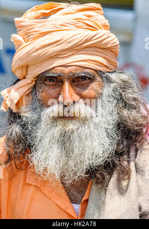 Close-up portrait of an elderly Indian man (Sadhu) in a vibrant orange outfit, capturing his wise expression, vertical headshot Stock Photo