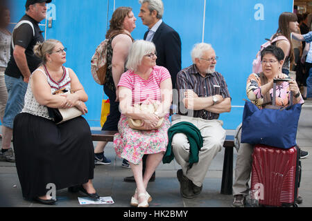 LONDON, ENGLAND - JULY 12, 2016 Old people in glasses sitting on bench in street. Have a little break Stock Photo