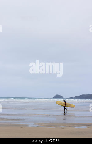 A lone surfer braves the cold and ventures into an empty lineup at Cornish Beach, Perranporth. Stock Photo