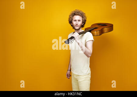 Portrait of smiling curly-haired man in casual clothes with guit Stock Photo
