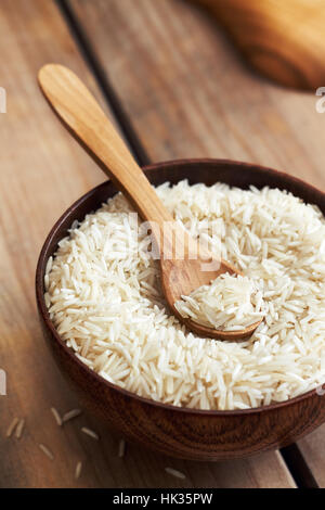 Raw uncooked basmati rice in wooden bowl on table Stock Photo