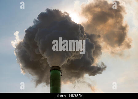 Factory flue and water steam on a blue sky background. Stock Photo