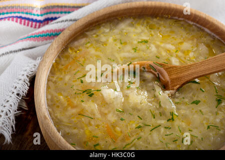Ukrainian sauerkraut soup kapusniak with millet on rustic table in wooden bowl, traditional winter soup Stock Photo