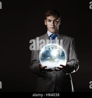 Young businessman holding Earth planet in hand. Elements of this image are furnished by NASA Stock Photo