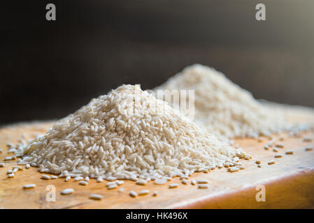 Two piles of white rice on wooden table background, metaphor ingredient, nutrition, carbohydrate food, agriculture concept, selective focus Stock Photo