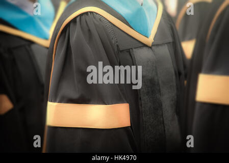 Selective focus on gowns of bachelor degree graduates in commencement graduation ceremony row, metaphor education, success, concept, background Stock Photo