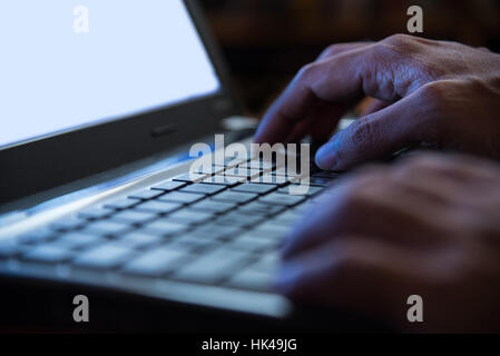 Selective focus on man two hand typing laptop/PC/computer keyboard in night dark tone low key Stock Photo