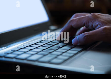 Selective focus on man hand typing laptop/PC/computer keyboard in night dark tone low key Stock Photo