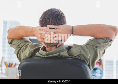 Rear view of a designer relaxing with foot on the desk in a modern office Stock Photo