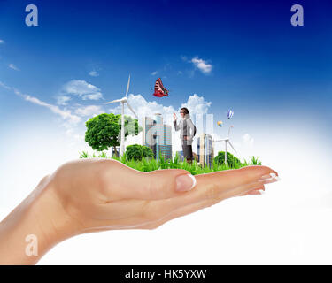 Collage with a human hand holding a green landscape Stock Photo - Alamy