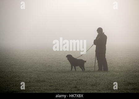Picker upper standing in field with trained dog, waiting for the pheasant shoot to start. Stock Photo