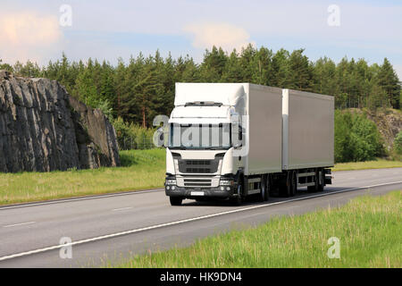 Big white cargo truck transports goods along motorway on a beautiful day of summer. Stock Photo