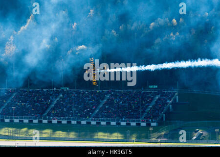 A stunt flying aeroplane, releasing smoke, is flying vertically in front of the grandstand during the Red Bull Air Race Stock Photo