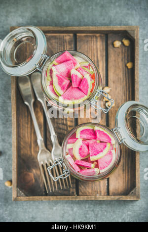 Healthy take-away lunch jars. Vegetable and chickpea sprout vegan salad in glass jars in wooden tray, grey concrete background, top view. Clean eating Stock Photo