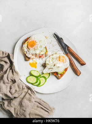 Breakfast toast with fried eggs with vegetables on white plate over grey marble background, top view. Healthy, clean eating, dieting food concept Stock Photo