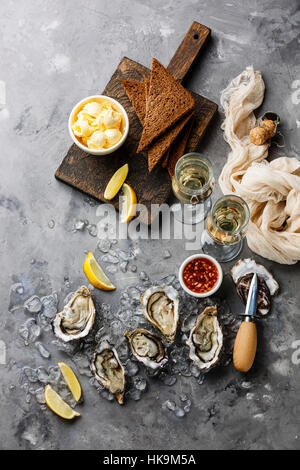Open Oysters with bread and butter and champagne on gray concrete texture background Stock Photo