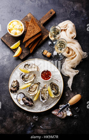 Open Oysters with bread and butter and champagne on dark texture background Stock Photo