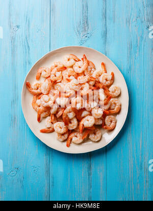 Prawns shrimps on white plate on blue background Stock Photo