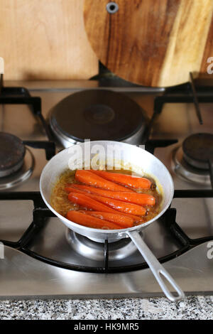Honey glazed Carrots in pan simmering in freshly squeezed orange juice to glaze