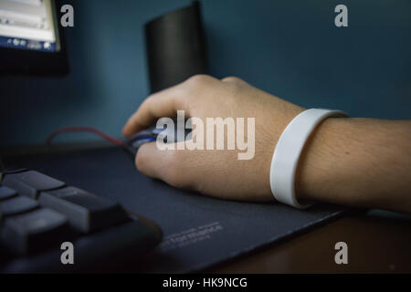 Male hand with bracelet holding computer mouse Stock Photo