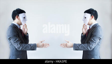 Two men in business suit handshaking with masks on - Business fraud and hypocrite agreement. Stock Photo
