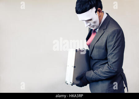 Businessman in disguise mask stealing a confidential suitcase - with copyspace. Stock Photo