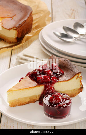 Cheesecake slice with cherry jam on wooden background Stock Photo