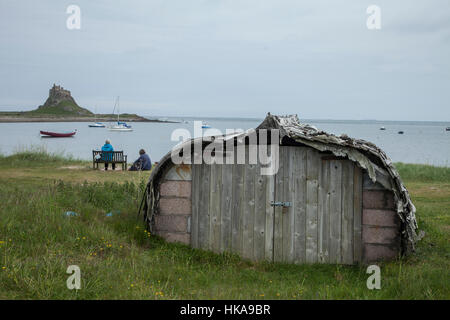 Lindisfarne Castle on Holy Island, Northumberland with un upturned boat hull used as a shed Stock Photo