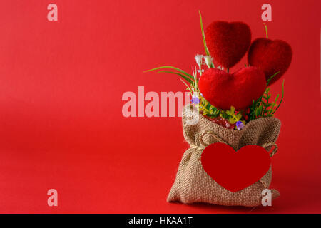 plastic bouquet and hearts in sack with a blank red paper are heart shapes isolated on red background Stock Photo