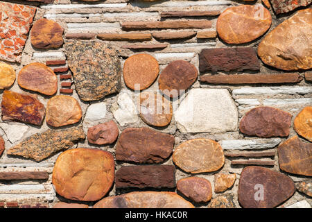 Close up of natural rocks and stone patterns and textures cemented on concrete wall background Stock Photo