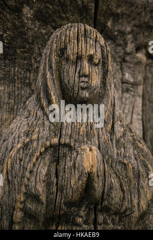 Virgin Mary carved on ancient wooden icon. The wooden figure of the Virgin Mary. Old wooden icon of the Virgin Mary with a close-up.  Cracked figurine Stock Photo