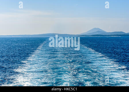 Wake water trail from a ferry ship in Croatia. Boat is leaving churning sea and waves behind. Blue ocean and skies on a sunny day. Stock Photo