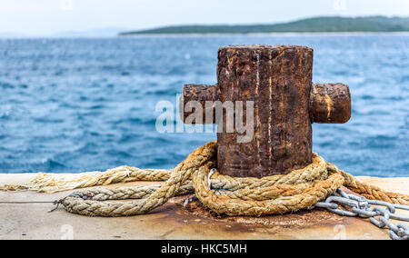 Old rusty steel mooring bollard pole on a pier. The best way for boat or ship mooring in harbor. Croatia, Silba. Stock Photo