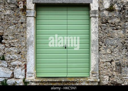 Old vintage green doors in a stone wall fence. Green panel door entrance to traditional courtyard on Silba Croatia. Stock Photo