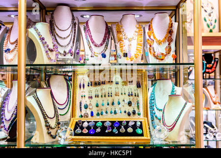 Display with different designs of handmade jewelry on stand. Close-up of handmade jewelry shop window display. Variety of Earrings, Necklace, rings, b Stock Photo
