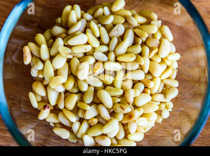 Pine nuts or seeds in glass bowl on wooden background. Close-up of pine nuts ready for serving or cooking. Stock Photo