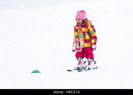 Little girl is learning to ski in ski resort. Child is skiing for the first time. Active children are happy. Stock Photo