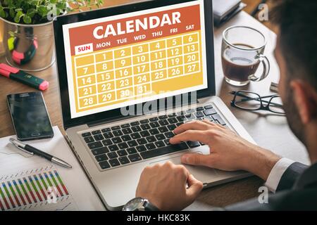 Man working on a laptop with calendar on the screen Stock Photo