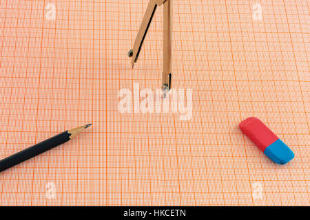On a sheet of graph paper are the compasses and a pencil with an eraser Stock Photo