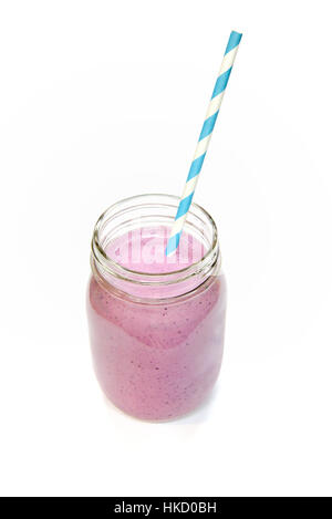 A fruit smoothie in a Mason jar with a blue and white spiral straw Stock Photo