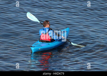 A kayaker in a blue Dagger Zydeco kayak, enjoying the waters of the Firth of Clyde in Scotland. Stock Photo