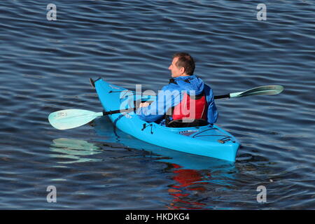 A kayaker in a blue Dagger Zydeco kayak, enjoying the waters of the Firth of Clyde in Scotland. Stock Photo