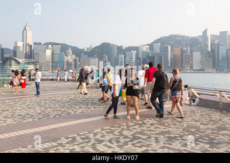 Hong Kong, Hong Kong - April 26 2015: Tourists take pictures and enjoy the famous Hong Kong island skyline across Victoria Harbour from the avenue of  Stock Photo