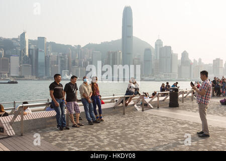 Hong Kong, Hong Kong - April 26 2015: Tourists take pictures and enjoy the famous Hong Kong island skyline across Victoria Harbour from the avenue of  Stock Photo