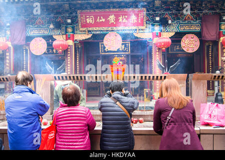 faithful in prayer while offering incense sticks  in  Sik Sik Yuen Wong Tai Sin temple in Hong Kong Stock Photo